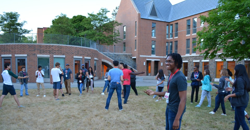 Large group of students on field participate in icebreaker activities