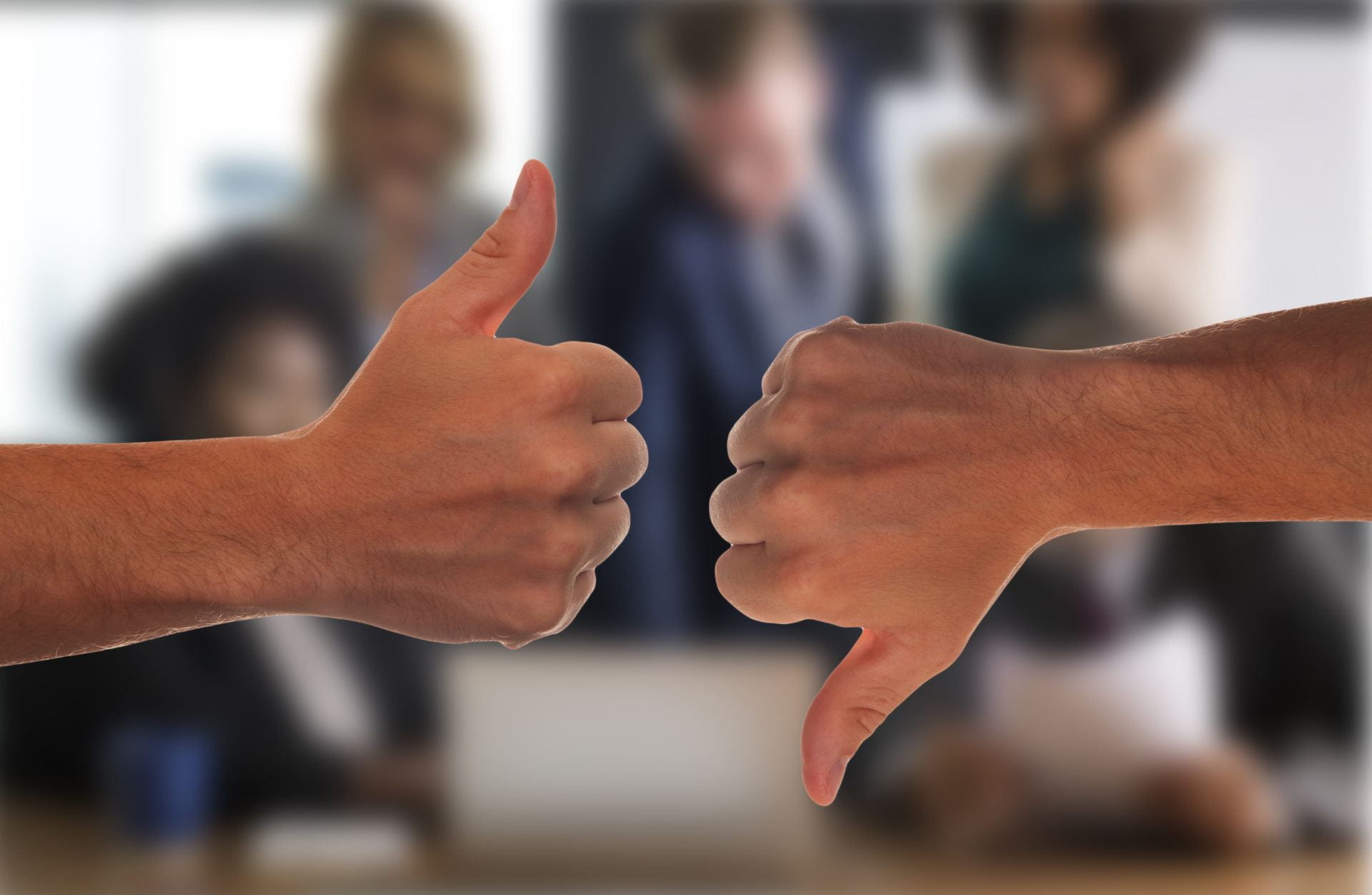 A photo of two hands: one with thumb up, the other with thumb down